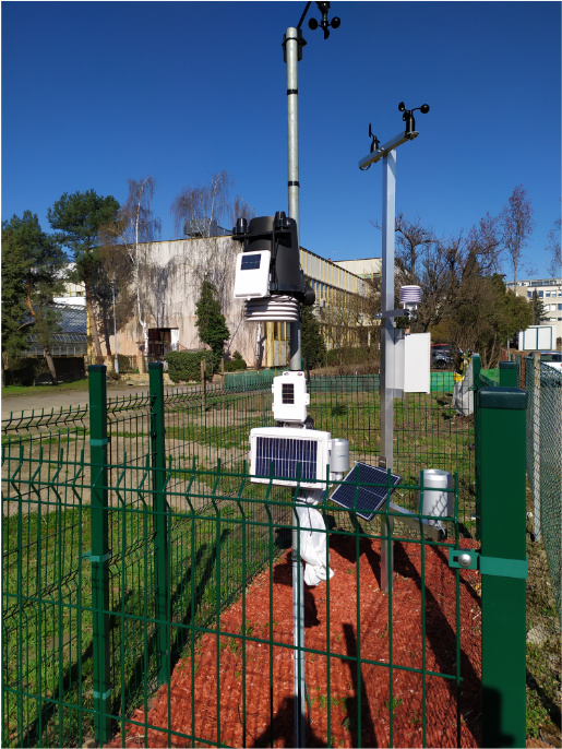 Konstrukcja z urządzeniami pomiarowymi stacji meteorologicznej. Stoi na ogrodzonym kawałku podłoża.