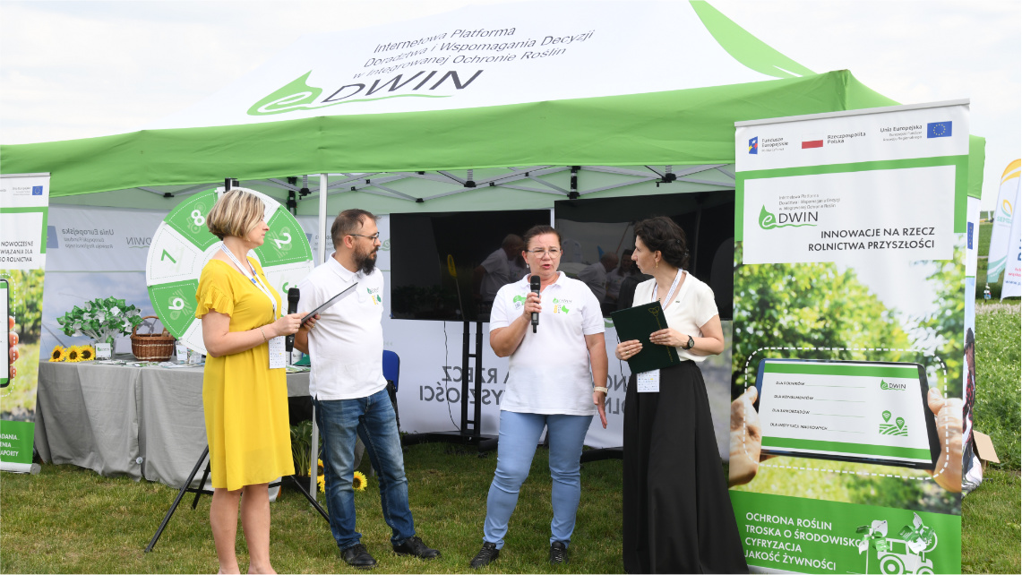 Doradcy WODR uczestniczą w nagraniu o platformie eDWIN, które odbywa się przy stoisku eDWIN. Obok nich stoją dwie dziennikarki.