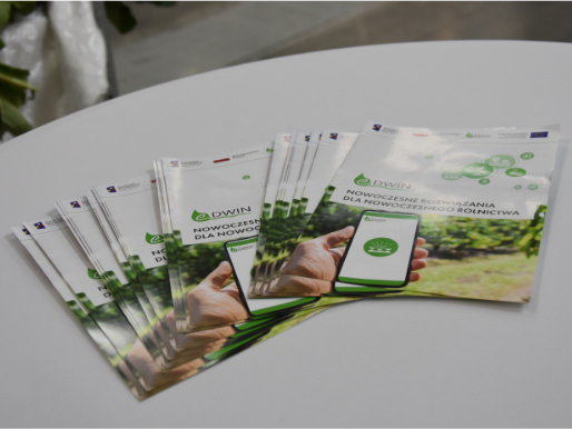 Stoisko eDWIN na Targach Bio Green Future Na stole, na białym obrusie leży kilkanaście ulotek promujących platformę doradczą eDWIN.